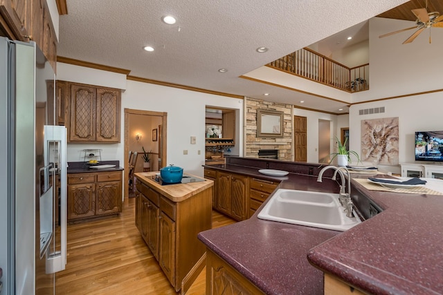17 Oriole Pl, North Mankato, MN 56003 - kitchen with a sink, stainless steel refrigerator with ice dispenser, a fireplace, a kitchen island, and black electric stovetop