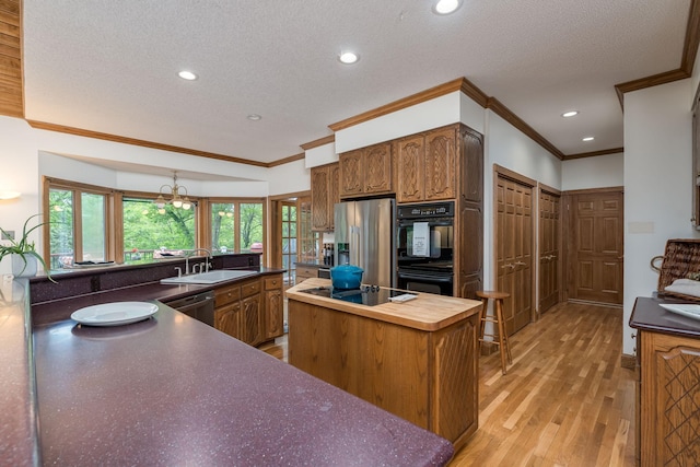 17 Oriole Pl, North Mankato, MN 56003 - kitchen with black appliances, a sink, a kitchen island, a textured ceiling, and light wood-style flooring