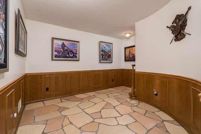 17 Oriole Pl, North Mankato, MN 56003 - hallway with a wainscoted wall, a textured ceiling, and wooden walls
