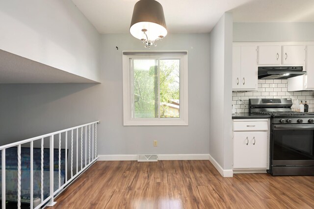 1158 Rockstone Ln, New Brighton, MN 55112 - kitchen with stainless steel gas range oven, under cabinet range hood, tasteful backsplash, wood finished floors, and baseboards