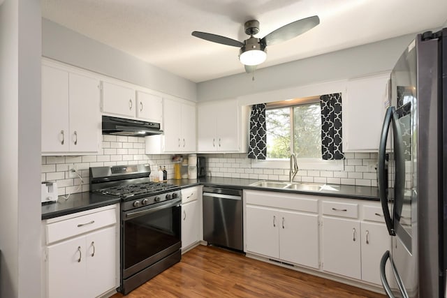 1158 Rockstone Ln, New Brighton, MN 55112 - kitchen with stainless steel appliances, under cabinet range hood, dark countertops, a sink, and decorative backsplash