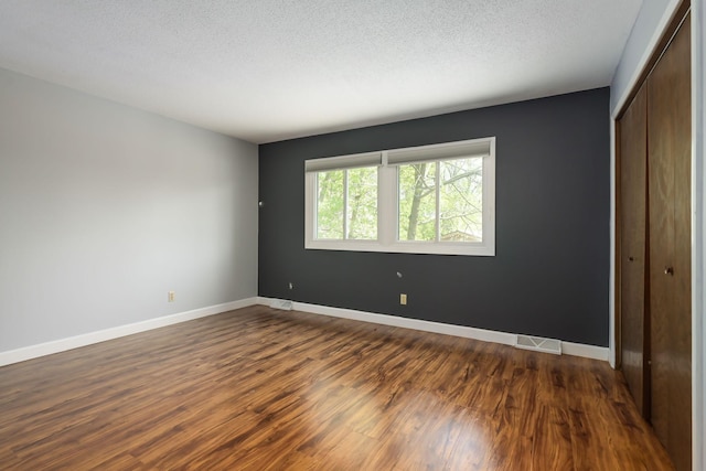 1158 Rockstone Ln, New Brighton, MN 55112 - unfurnished bedroom with a closet, dark wood-style floors, baseboards, and a textured ceiling