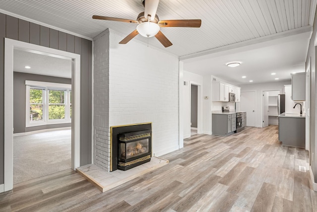 11600 Timberline Rd, Minnetonka, MN 55305 - unfurnished living room with a sink, a ceiling fan, light wood finished floors, a fireplace, and baseboards