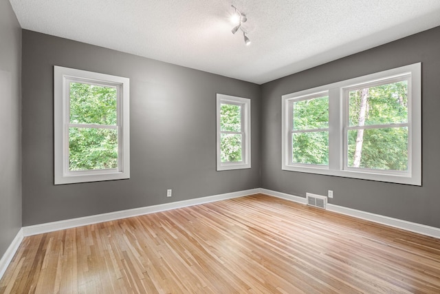 11600 Timberline Rd, Minnetonka, MN 55305 - empty room with light wood-style flooring, baseboards, track lighting, and a textured ceiling