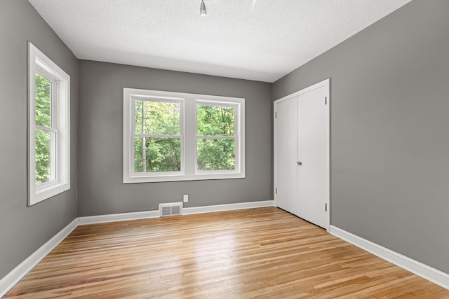 11600 Timberline Rd, Minnetonka, MN 55305 - unfurnished bedroom with light wood finished floors, a textured ceiling, baseboards, and a closet
