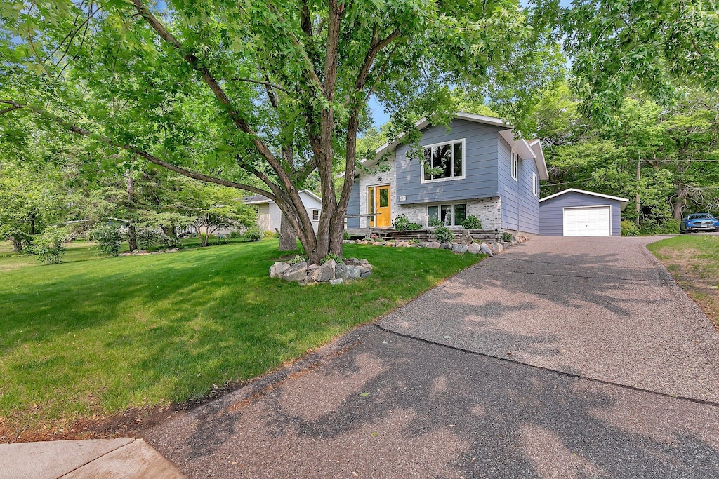 612 3rd Ave NE, Sartell, MN 56377 - tri-level home featuring an outdoor structure, a garage, driveway, and a front lawn