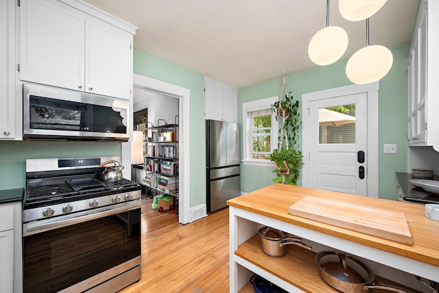 1144 Abell St, Saint Paul, MN 55117 - kitchen featuring appliances with stainless steel finishes, white cabinets, light wood-type flooring, hanging light fixtures, and baseboards