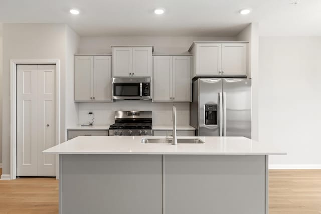 6679 Bluestem Way, Minnetrista, MN 55331 - kitchen with stainless steel appliances, a sink, light wood-style flooring, decorative backsplash, and light countertops