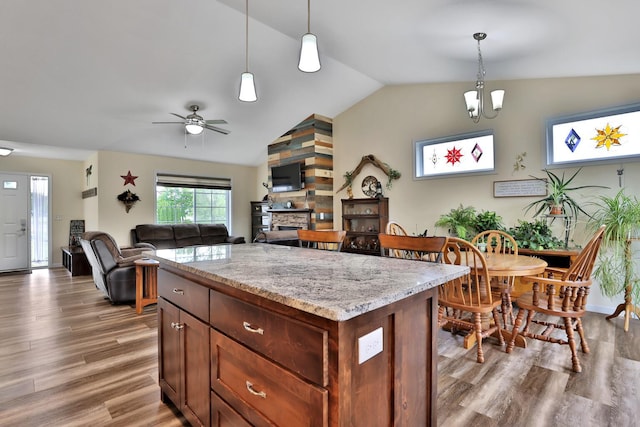 1217 Blossom Blvd NW, Isanti, MN 55040 - kitchen featuring a fireplace, lofted ceiling, wood finished floors, hanging light fixtures, and light stone counters