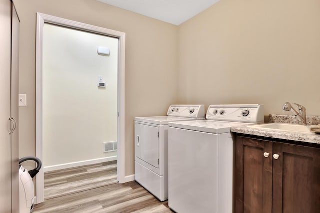 1217 Blossom Blvd NW, Isanti, MN 55040 - laundry area with independent washer and dryer, light wood-style floors, baseboards, and cabinet space