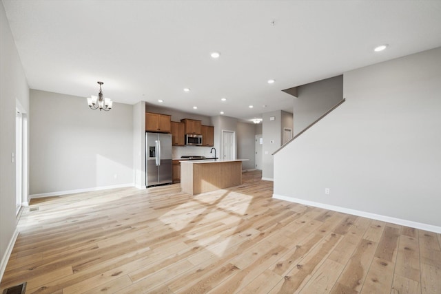 6683 Bluestem Way, Minnetrista, MN 55331 - kitchen featuring appliances with stainless steel finishes, a chandelier, open floor plan, light wood-style floors, and light countertops