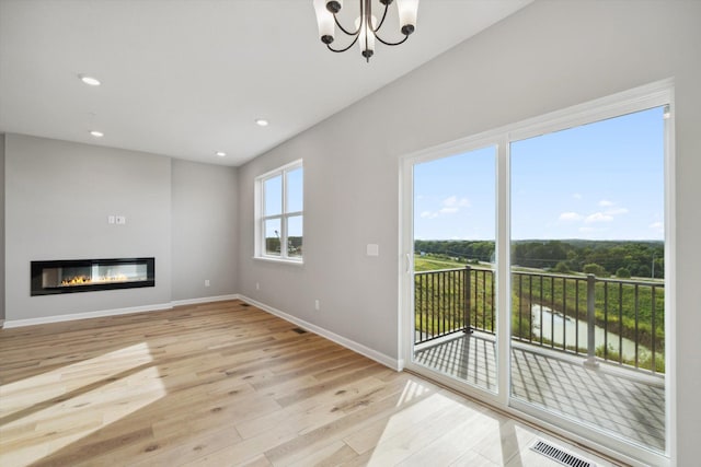 6683 Bluestem Way, Minnetrista, MN 55331 - unfurnished living room featuring wood finished floors, a chandelier, baseboards, recessed lighting, and a glass covered fireplace