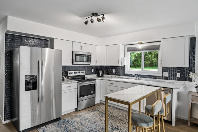 701 Auburn Pl NW, Elk River, MN 55330 - kitchen with appliances with stainless steel finishes, decorative backsplash, white cabinetry, light stone counters, and wood finished floors