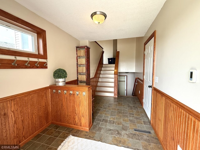 103 Highview Dr, Dassel, MN 55325 - hall featuring wainscoting, stairway, a textured ceiling, dark stone finish floors, and wood walls