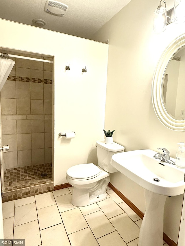 103 Highview Dr, Dassel, MN 55325 - bathroom featuring a tile shower, toilet, baseboards, a textured ceiling, and tile patterned flooring