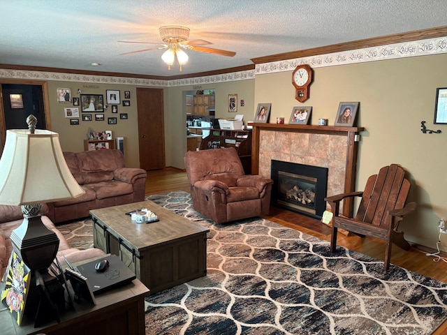 505 Lindquist St W, Onamia, MN 56359 - living room with ceiling fan, wood finished floors, a textured ceiling, crown molding, and a tile fireplace