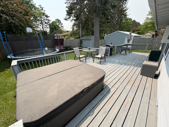 505 Lindquist St W, Onamia, MN 56359 - deck with a trampoline, a covered hot tub, a grill, and outdoor dining area