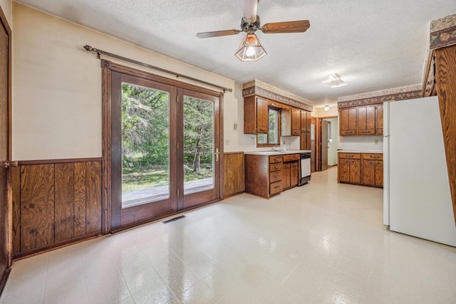 4399 124th Ave, Clear Lake, MN 55319 - kitchen featuring white appliances, a textured ceiling, brown cabinets, wainscoting, and light countertops