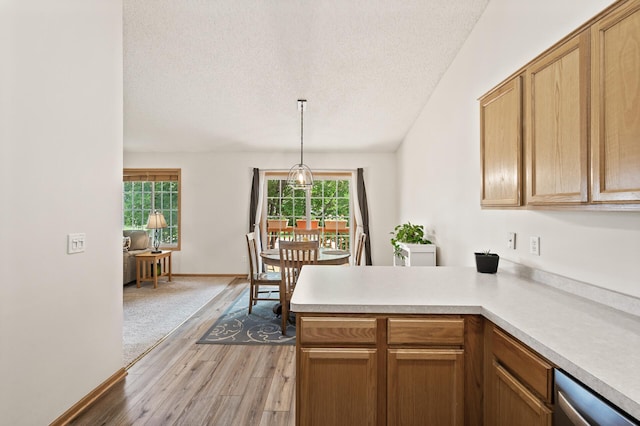 13408 Ximines Ln N, Champlin, MN 55316 - kitchen with light wood-type flooring, a textured ceiling, a peninsula, light countertops, and decorative light fixtures