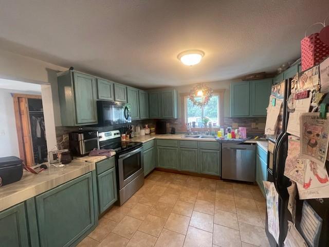 806 Central Ave N, Park Rapids, MN 56470 - kitchen featuring green cabinetry, stainless steel appliances, backsplash, a sink, and tile counters