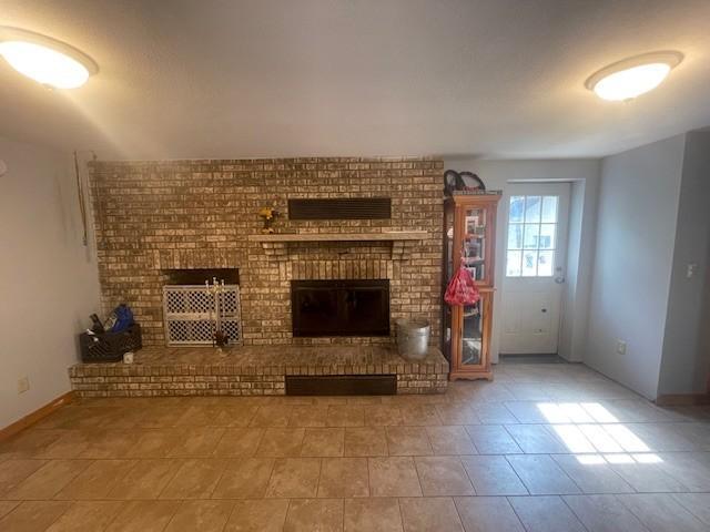 806 Central Ave N, Park Rapids, MN 56470 - unfurnished living room with a brick fireplace, tile patterned flooring, and baseboards