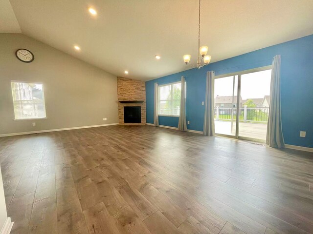 8521 Titanium Cir, Woodbury, MN 55129 - unfurnished living room featuring wood finished floors, a chandelier, vaulted ceiling, a stone fireplace, and baseboards