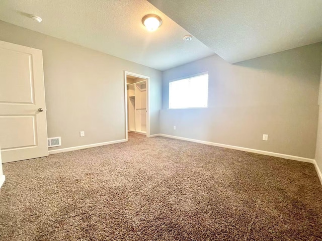 8521 Titanium Cir, Woodbury, MN 55129 - unfurnished bedroom with carpet flooring, baseboards, a walk in closet, a textured ceiling, and a closet