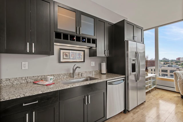 215 10th Ave S Unit 730, Minneapolis, MN 55415 - kitchen with stainless steel appliances, light wood finished floors, dark cabinets, glass insert cabinets, and light stone counters