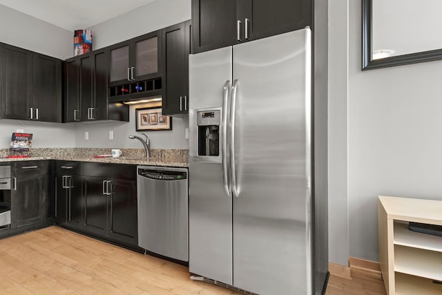 215 10th Ave S Unit 730, Minneapolis, MN 55415 - kitchen with appliances with stainless steel finishes, light stone countertops, light wood-type flooring, and dark cabinets