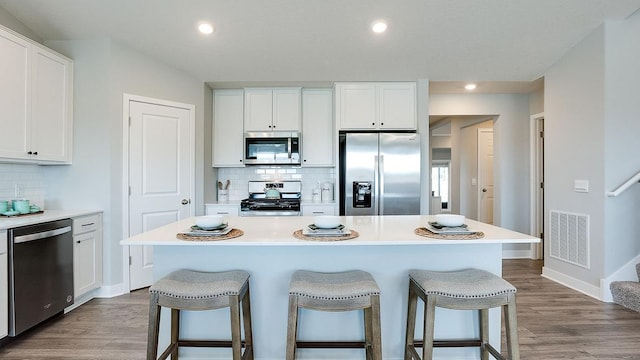 8863 Jorgensen Ave S, Cottage Grove, MN 55016 - kitchen featuring stainless steel appliances, a kitchen bar, tasteful backsplash, white cabinets, and recessed lighting