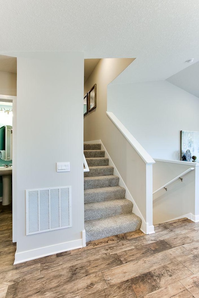 8863 Jorgensen Ave S, Cottage Grove, MN 55016 - stairs featuring wood finished floors, a textured ceiling, baseboards, and lofted ceiling