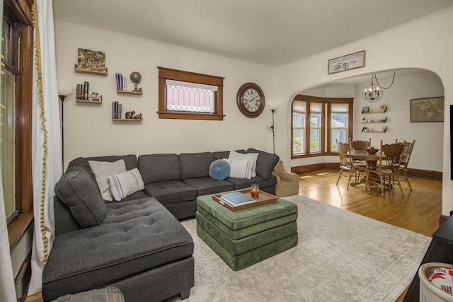 1023 Avon St N, Saint Paul, MN 55103 - living room featuring arched walkways, a chandelier, wood finished floors, healthy amount of natural light, and crown molding