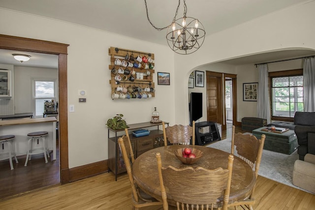1023 Avon St N, Saint Paul, MN 55103 - dining area featuring arched walkways, light wood-type flooring, plenty of natural light, and a chandelier