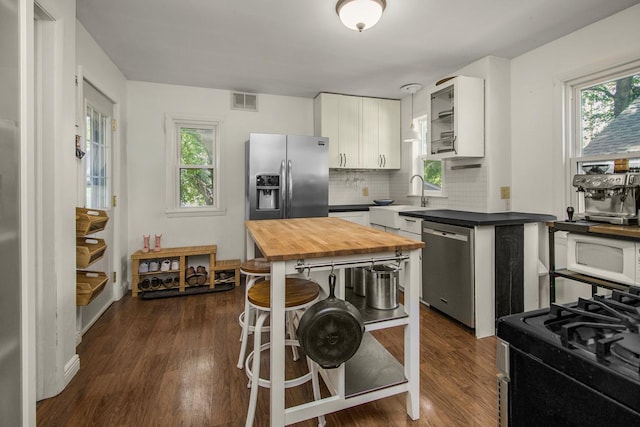 1023 Avon St N, Saint Paul, MN 55103 - kitchen with stainless steel appliances, butcher block counters, white cabinetry, backsplash, and dark wood finished floors