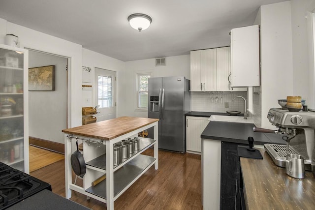 1023 Avon St N, Saint Paul, MN 55103 - kitchen featuring stainless steel refrigerator with ice dispenser, white cabinets, dark countertops, decorative backsplash, and dark wood-style flooring