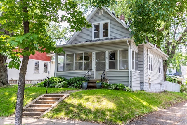 1023 Avon St N, Saint Paul, MN 55103 - bungalow-style house featuring a chimney, a front yard, a sunroom, and entry steps