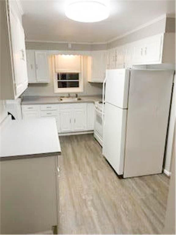 587 Bay St, Saint Paul, MN 55102 - kitchen with freestanding refrigerator, light wood-style flooring, light countertops, range, and white cabinetry