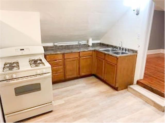 587 Bay St, Saint Paul, MN 55102 - kitchen with gas range gas stove, brown cabinetry, and light wood-style floors