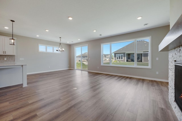 15354 112th Ave N, Dayton, MN 55369 - unfurnished living room featuring a stone fireplace, wood finished floors, a chandelier, baseboards, and recessed lighting