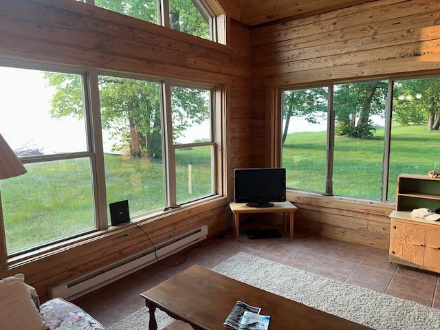 19373 Ethel Beach Rd NE, Kelliher, MN 56650 - sunroom / solarium featuring a baseboard radiator, wood walls, tile patterned flooring, and healthy amount of natural light