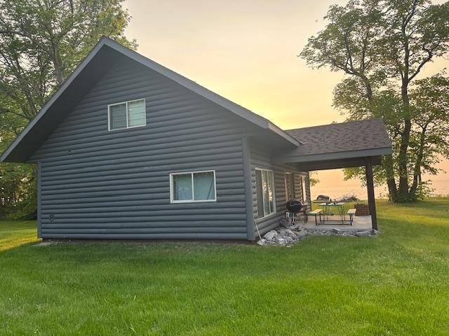19373 Ethel Beach Rd NE, Kelliher, MN 56650 - back of property at dusk with a patio area, a yard, and log veneer siding