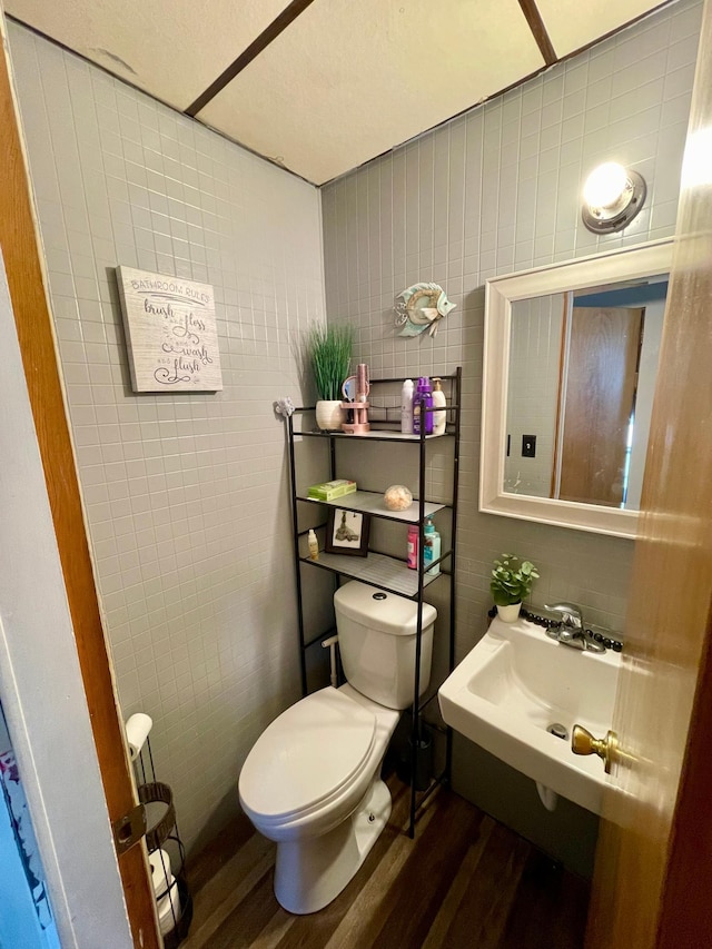 506 3rd St SW, Wadena, MN 56482 - bathroom with wood finished floors, toilet, tile walls, and a sink