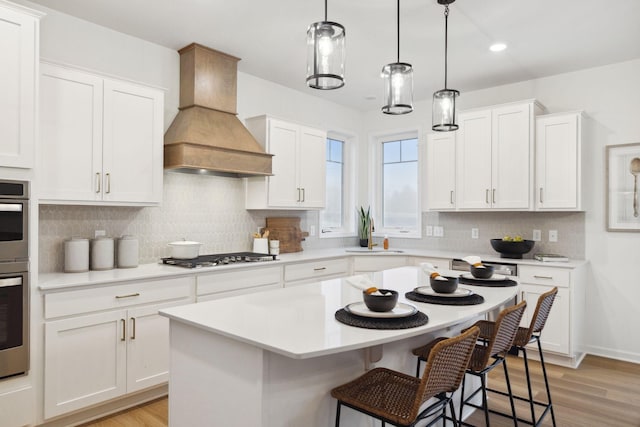 6640 Wolfberry Curv, Minnetrista, MN 55331 - kitchen featuring premium range hood, stainless steel gas cooktop, a kitchen bar, light countertops, and white cabinetry