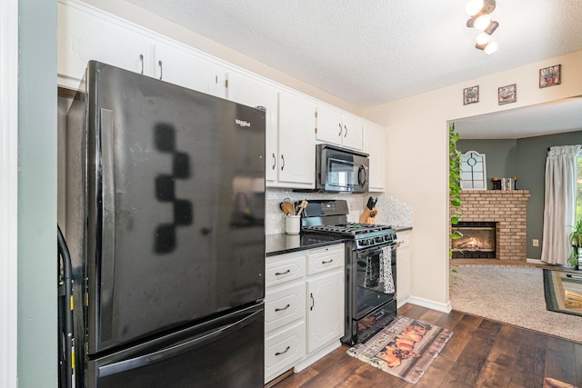 12233 191st Ave NW, Elk River, MN 55330 - kitchen with black appliances, dark wood-style floors, white cabinetry, a textured ceiling, and a brick fireplace