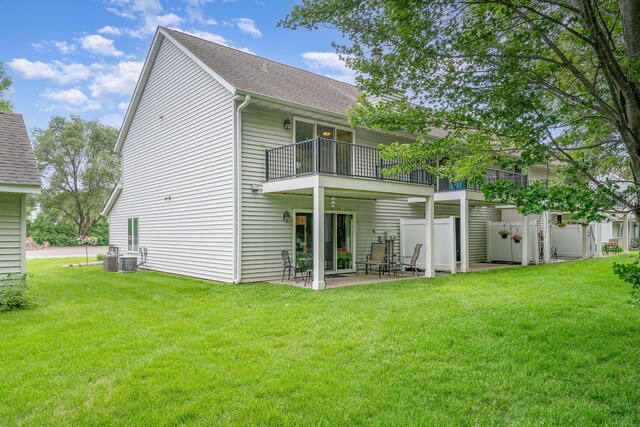 12233 191st Ave NW, Elk River, MN 55330 - back of house featuring a balcony, a lawn, a patio, a shingled roof, and cooling unit
