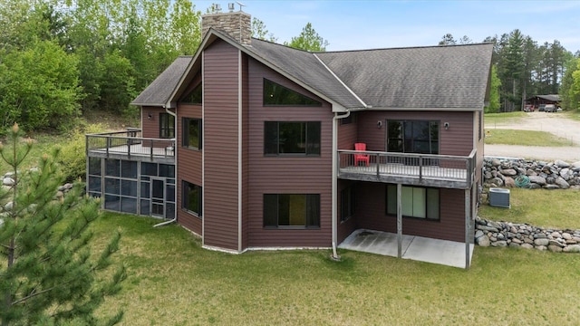 32305 Little E Lake Rd, Bigfork, MN 56628 - rear view of house featuring a patio area, a chimney, a lawn, roof with shingles, and a balcony