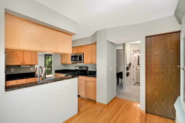 4839 Spring Cir, Minnetonka, MN 55345 - kitchen featuring appliances with stainless steel finishes, light wood-style floors, a peninsula, dark stone counters, and light brown cabinets