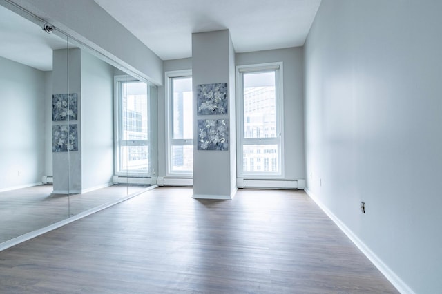 433 7th St Unit 2317, Minneapolis, MN 55415 - unfurnished living room featuring wood finished floors, baseboards, and a baseboard heating unit