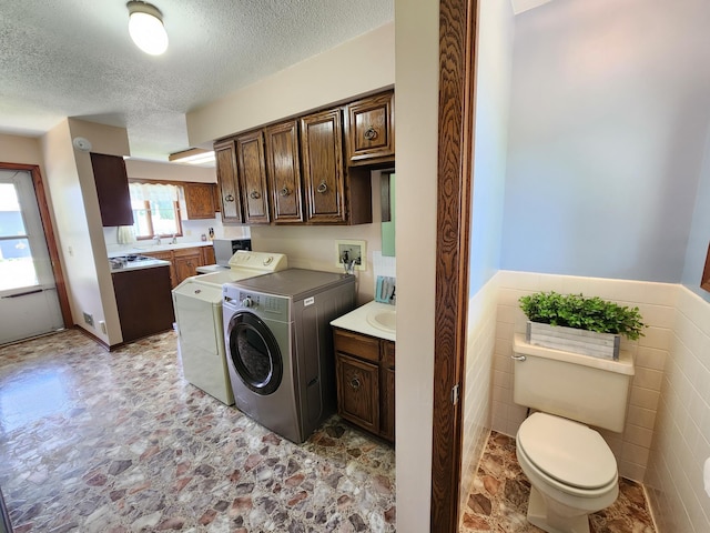 25 3rd Ave NE, Plainview, MN 55964 - washroom with washing machine and clothes dryer, a textured ceiling, a wainscoted wall, tile walls, and light stone finish floors