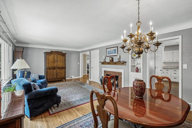 611 Sumter Ave S, Golden Valley, MN 55426 - dining area with wood finished floors, a chandelier, and a brick fireplace